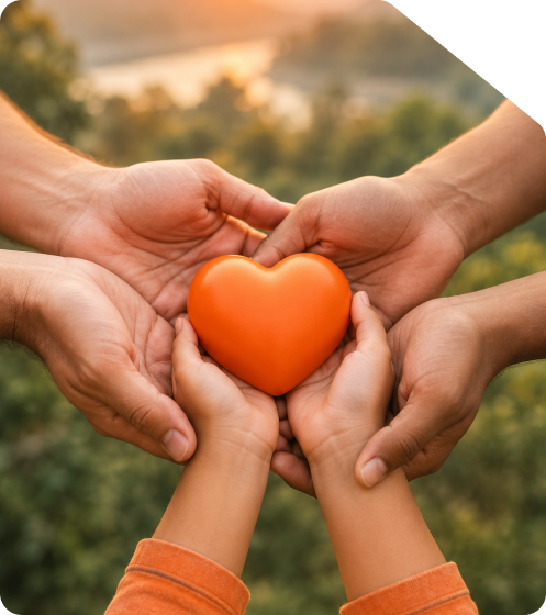 Multiple diverse hands holding an orange heart symbol outdoors representing non-profit Section 8 company registration and social welfare in India