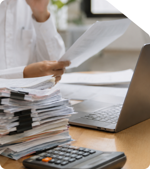 Professional reviewing financial invoices and documents with a laptop and calculator for online GST return filing